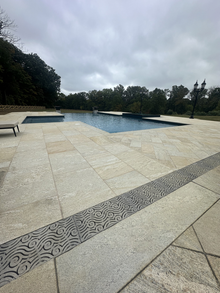 Cast aluminum trench grates in decorative Argo pattern by Iron Age Designs. Pool deck installation.