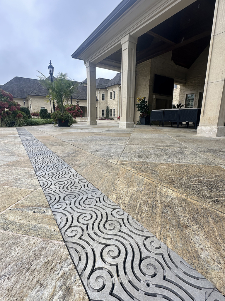 Cast aluminum trench grates in decorative Argo pattern by Iron Age Designs. Pool deck installation.