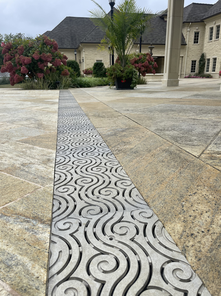 Cast aluminum trench grates in decorative Argo pattern by Iron Age Designs. Pool deck installation.