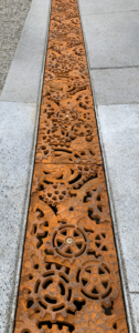 Decorative cast iron trench grates featuring interlocking gear pattern