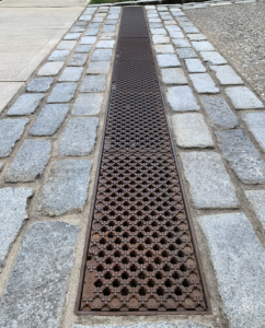 Decorative cast iron trench grate with grid pattern topped by 4-petal flowers