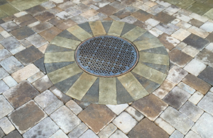 Decorative cast iron catch basin grate surrounded by pavers