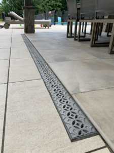 Decorative cast aluminum trench grates with Interlaken pattern installed in pool patio