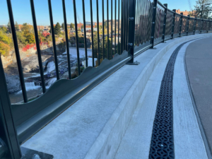 Decorative cast iron trench grates in Interlaken pattern with black powder coat finish.