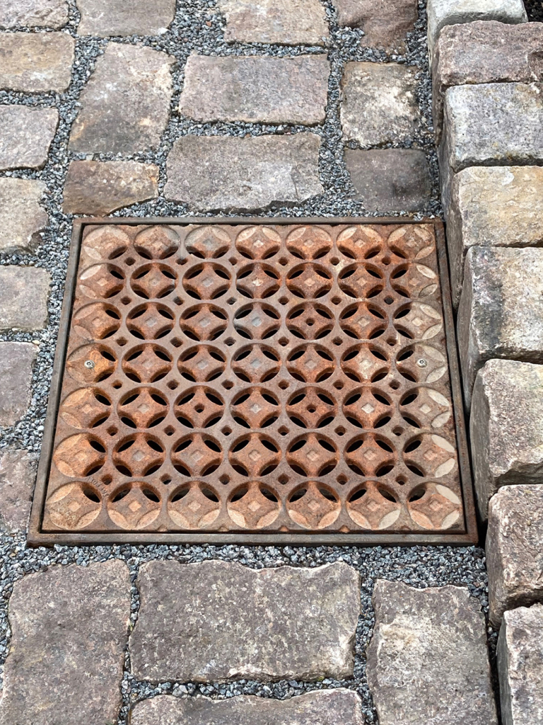 Cast iron catch basin grate in decorative Interlaken pattern by Iron Age Designs.