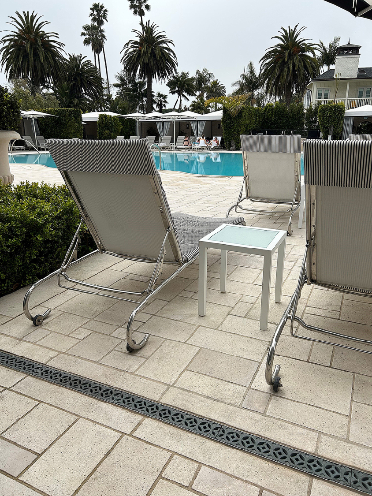 Cast bronze trench grates in decorative Interlaken pattern from Iron Age Designs. Installed on pool deck surrounded by pavers.