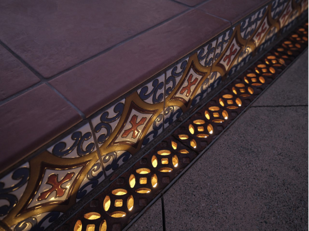 Cast iron trench grate in decorative Interlaken pattern by Iron Age Designs. Lighting installed beneath the grates.