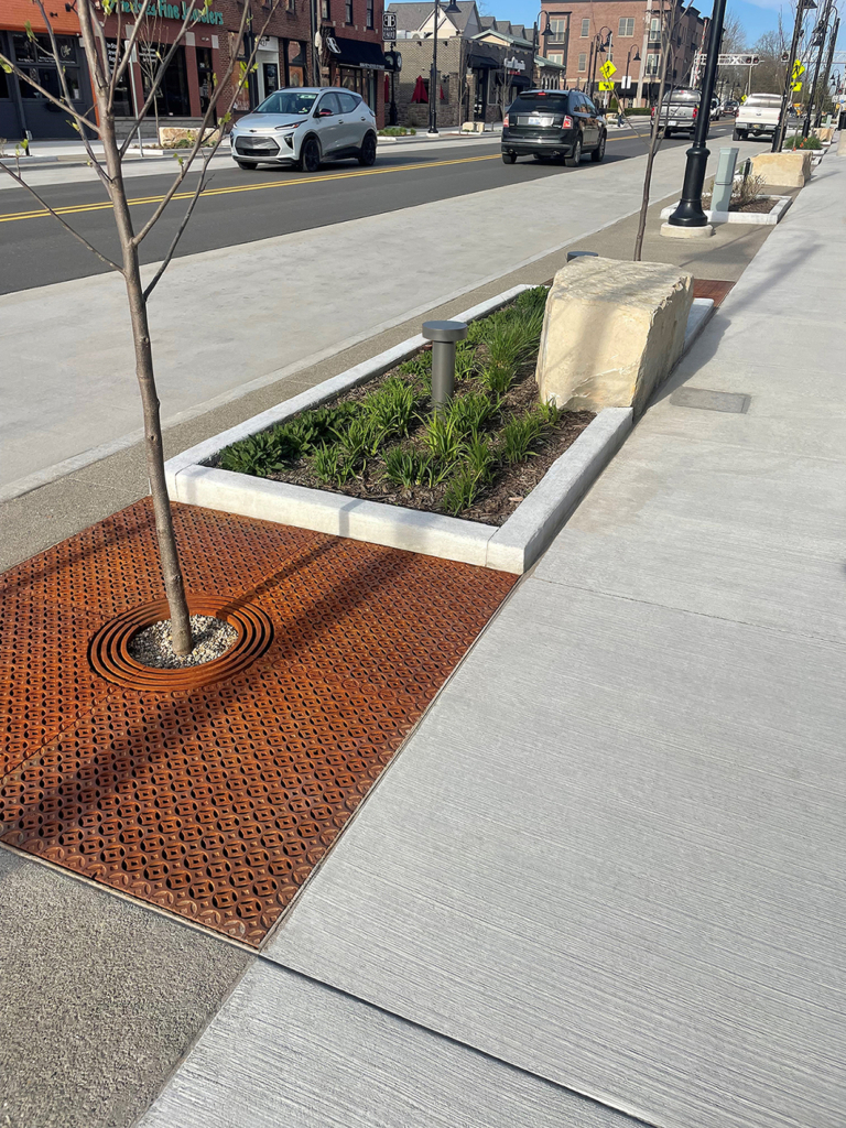 Raw cast iron tree grate in decorative Interlaken pattern from Iron Age Designs. Streetscape installation.