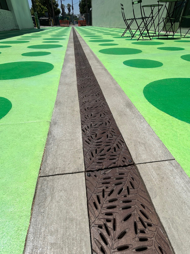 Cast iron trench grates in decorative Locust pattern by Iron Age Designs. Installed in colorful pedestrian plaza.