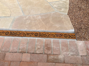 Decorative cast iron trench grate installed in paver patio