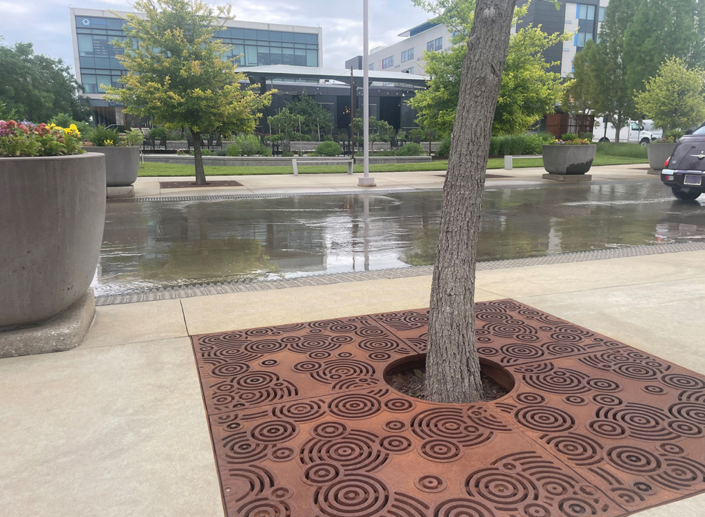 Cast iron tree grate in decorative Oblio pattern from Iron Age Designs. Installed in community plaza.