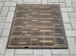 Decorative cast iron catch basin grate in Rain pattern