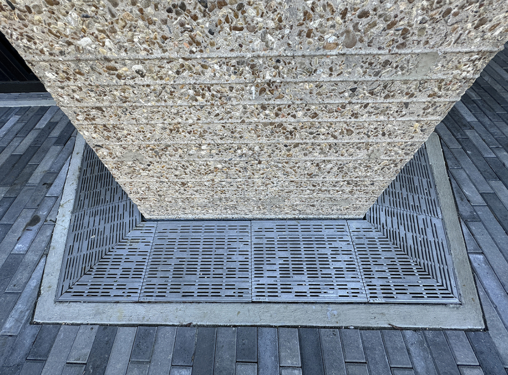 Cast iron trench grate in decorative Rain pattern from Iron Age Designs. Installed in building entryway.
