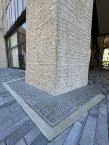 Cast iron trench grate in decorative Rain pattern from Iron Age Designs. Installed in building entryway.