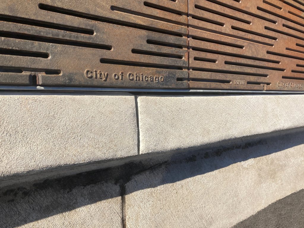 Cast iron tree grate in decorative Rain pattern by Iron Age Designs. Grates customized with "City of Chicago" branding.