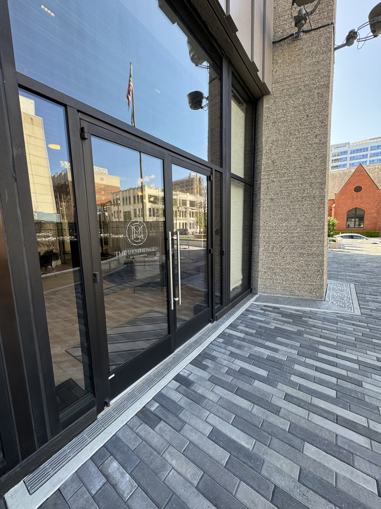 Cast iron trench grate in decorative Rain pattern from Iron Age Designs. Installed in building entryway.