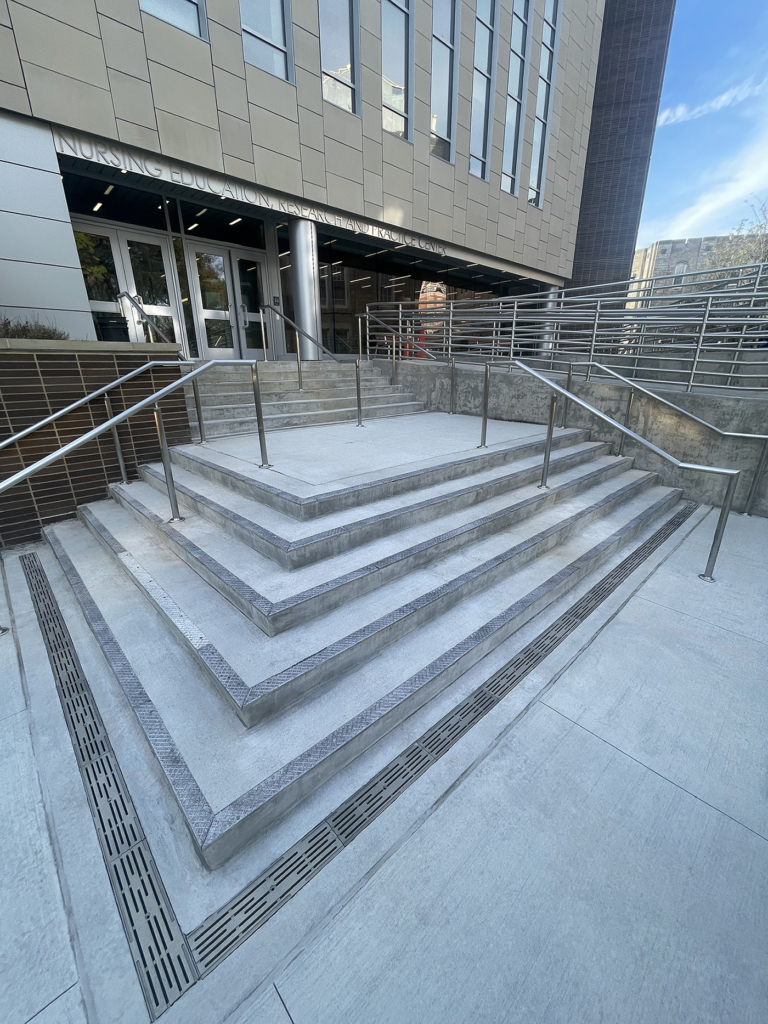Cast aluminum decorative trench grates in Rain pattern from Iron Age Designs in college courtyard.