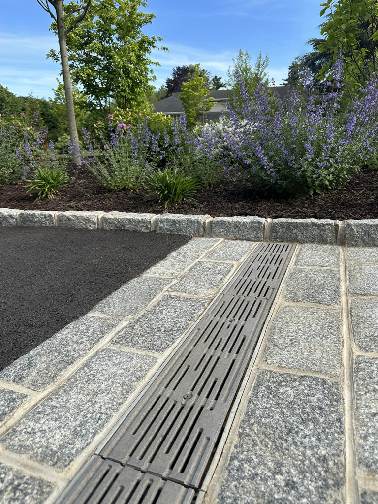 Raw cast aluminum trench grate in decorative Rain pattern from Iron Age Designs. Residential driveway installation.