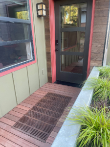 Decorative cast iron catch basin grate in Regular Joe pattern, installed as a walk off mat in front of a residential entryway