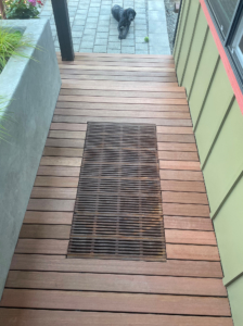 Decorative cast iron catch basin grate in Regular Joe pattern, installed as a walk off mat in front of a residential entryway