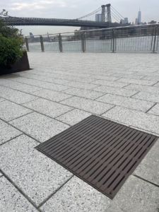 Cast iron drain grates in linear Regular Joe pattern, with Brooklyn Bridge in the background