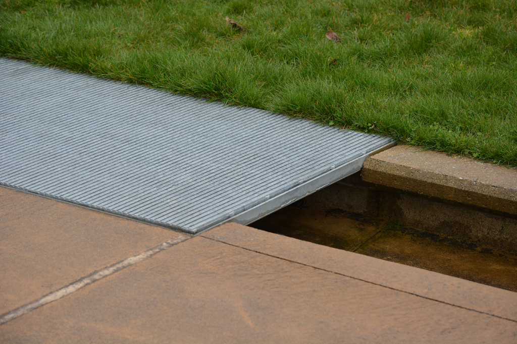 Raw cast aluminum drain grates in linear Regular Joe pattern