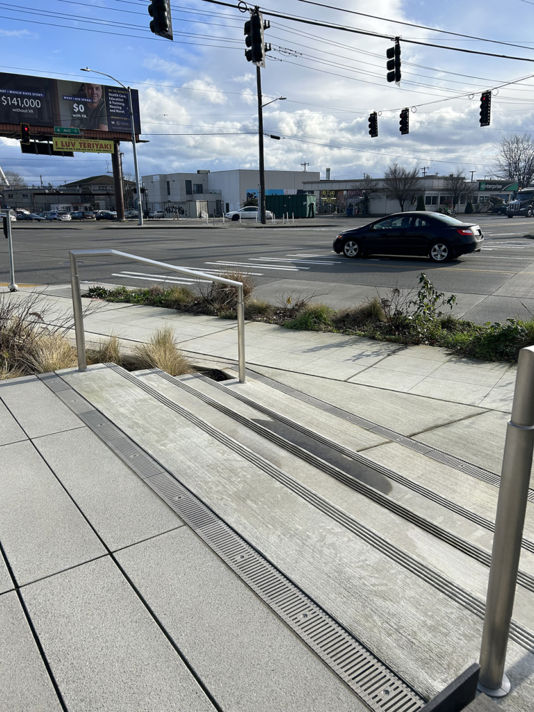 Cast aluminum trench grate in Regular Joe pattern from Iron Age Designs at top of concrete entry stairs.