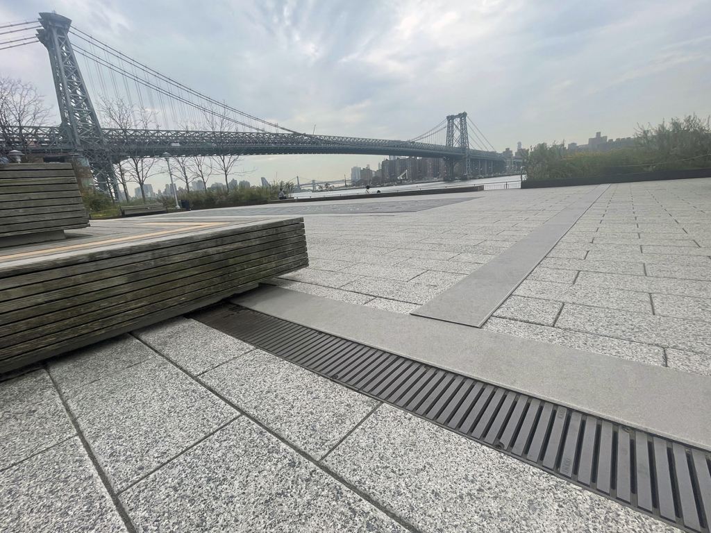 Cast iron trench drain grates in linear Regular Joe pattern, with Brooklyn Bridge in the background