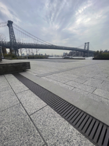Cast iron trench drain grates in linear Regular Joe pattern, with Brooklyn Bridge in the background