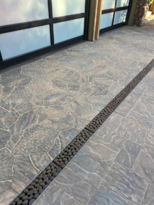 Decorative cast iron trench grates in River Rock pattern, installed in residential driveway