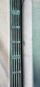 Cast bronze trench grates in water feature, aged 7 years, showing verdigris finish. Que pattern by Iron Age Designs.