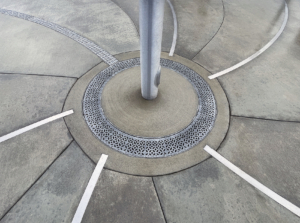 Cast aluminum radius trench drain grates in decorative Interlaken pattern, installed around flagpole