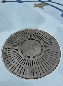 Cast aluminum catch basin grate in decorative Moon Face pattern by Iron Age Designs.