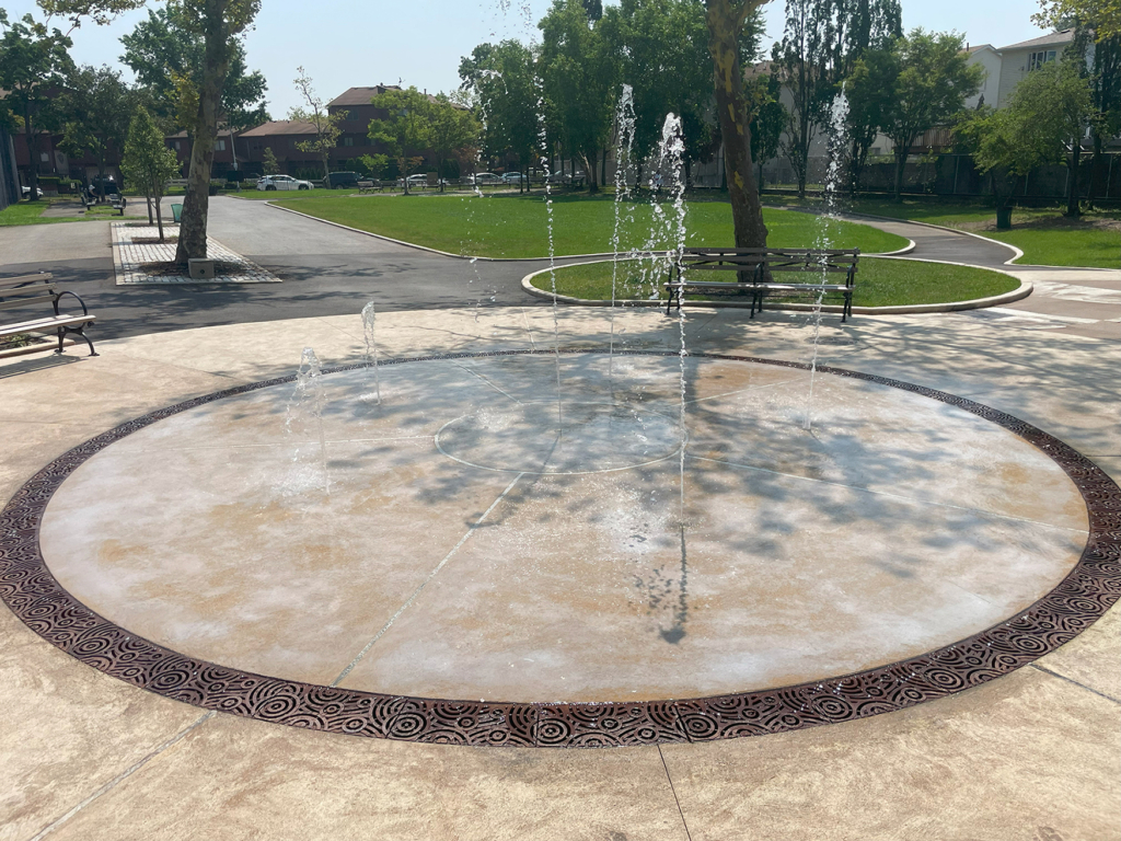 Cast iron radius trench grate in decorative Oblio pattern from Iron Age Designs. Installed in splash park.