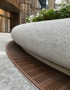 Decorative cast bronze radius trench grates in Que pattern surrounding circular planter in front of One Vanderbilt building