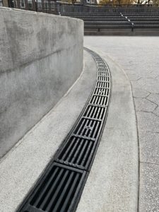 Cast iron radius trench drain grates in a linear Que pattern, black powder coat finish.