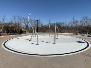 Cast iron radius trench grate with powder coat finish in ellipse shape around a spray park