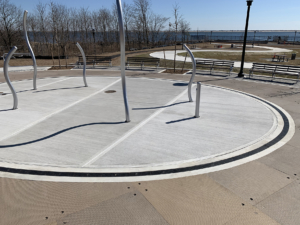 Cast iron radius trench grate with powder coat finish in ellipse shape around a spray park