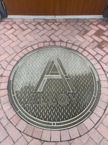 Cast bronze plaque with "A" in front of entryway to Alloy Apartments