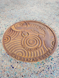 Cast iron custom plaque for Calabazas Creek with fish swimming over circular Oblio pattern
