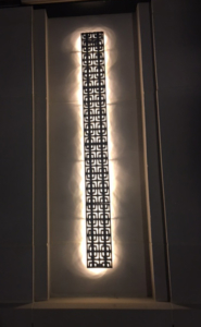 Cast iron, powder coated Carbochon drain grate shown used as lighting sconce on outside of building