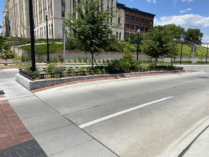 Decorative planter in road median on college campus, surrounded by custom cast iron planter fence.