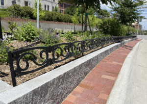 Decorative planter in road median on college campus, surrounded by custom cast iron planter fence.