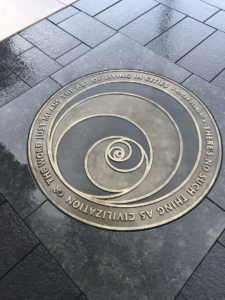Custom cast bronze plaque with stylized rose design that says "There's no such thing as civilization. The world just means the art of living in cities" Roger Zelazny