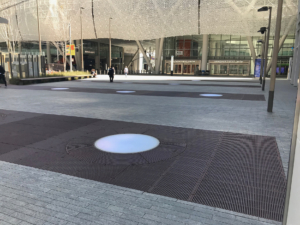 Cast iron grates surrounding LED lights, all installed in a pedestrian plaza