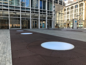 Cast iron grates surrounding LED lights, all installed in a pedestrian plaza