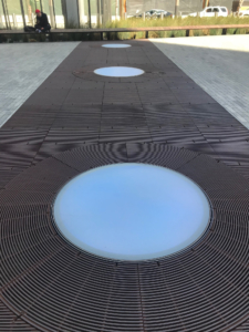 Cast iron grates surrounding LED lights, all installed in a pedestrian plaza