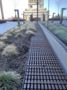Cast iron trench drain grate in linear Plex pattern. Shown in rooftop garden.