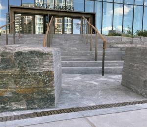 Decorative cast iron trench grate in Plex pattern installed in pavers in front of building entrance