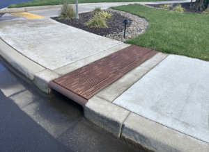 Cast iron curb inlet with decorative Rain trench drain grates cutting across the sidewalk